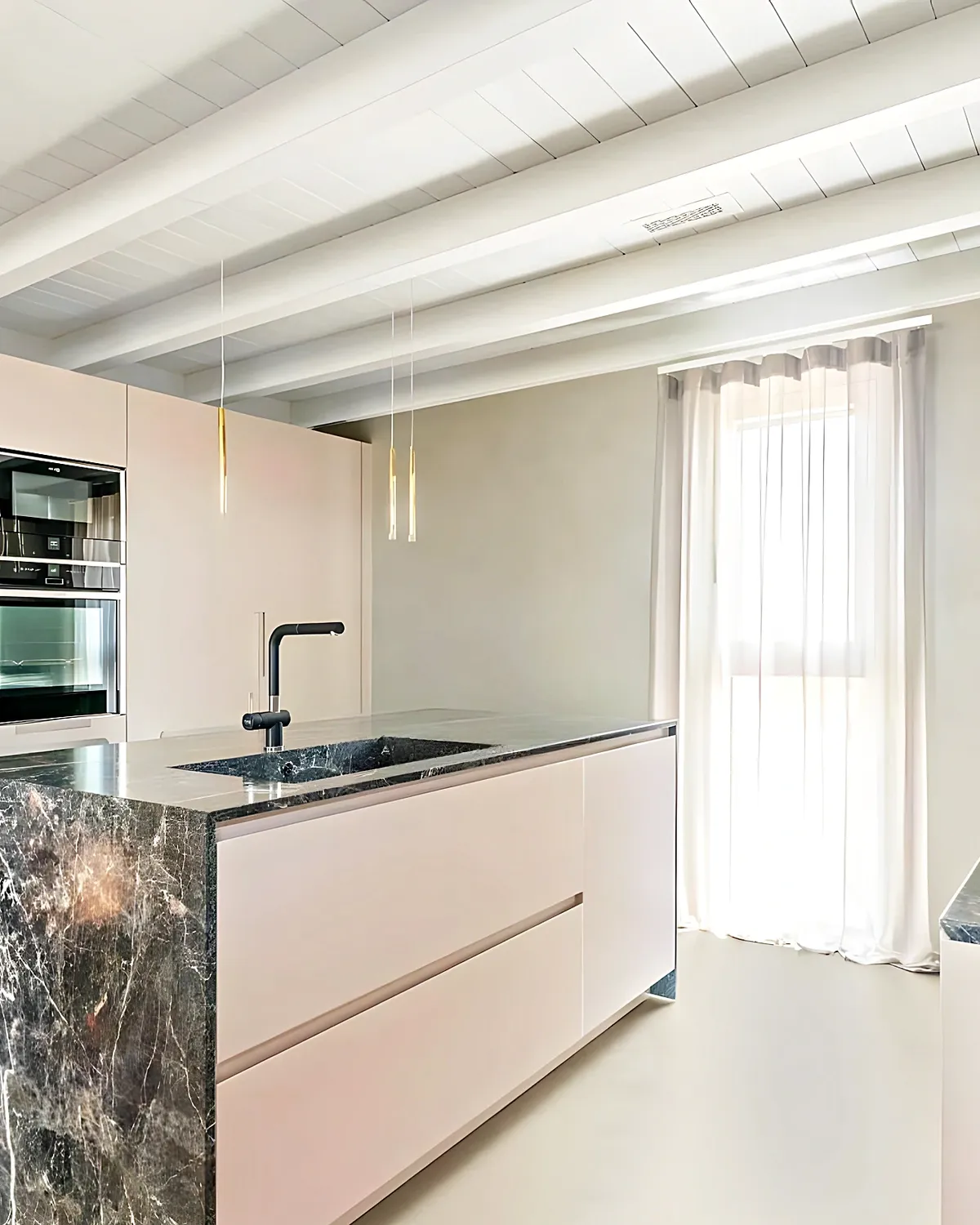 Kitchen with a marble island and white units in a renovated Vilanova i la Geltrú apartment
